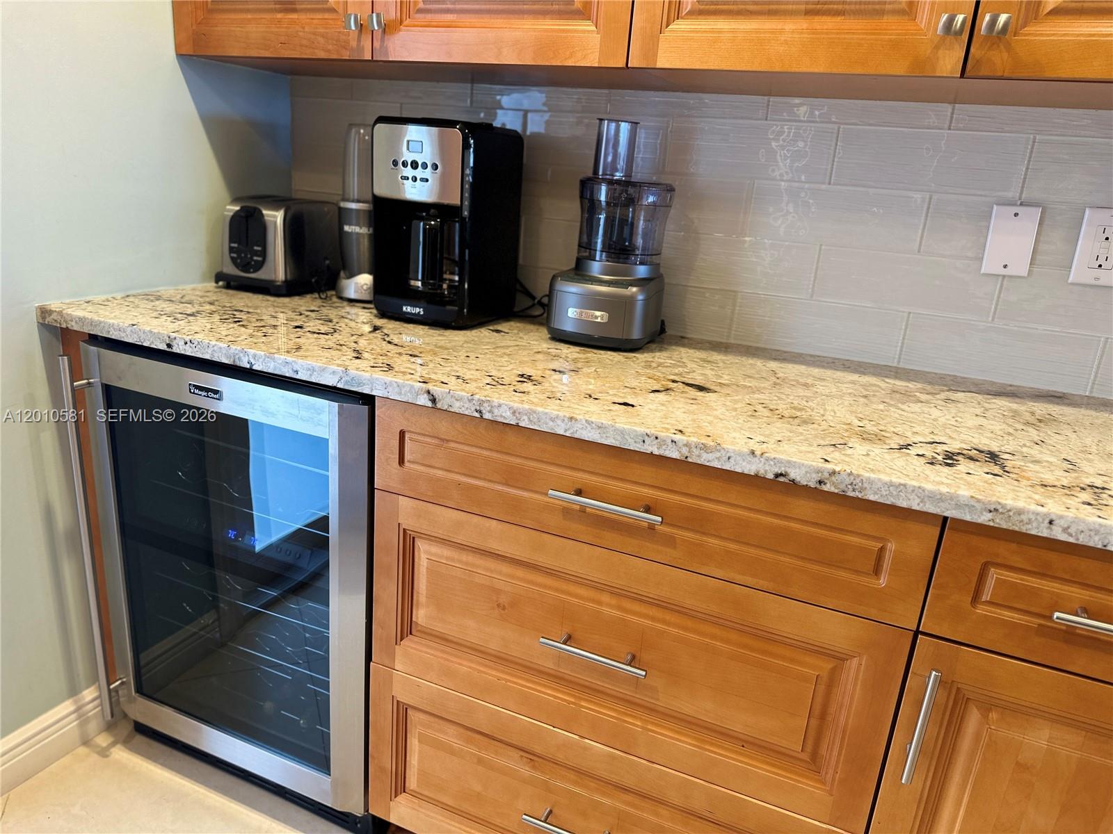 A kitchen features wood cabinets, granite countertops, stainless steel appliances, and a glass door — 750 N Ocean Blvd # 310, Pompano Beach FL 33062, POMPANO BEACH, FL