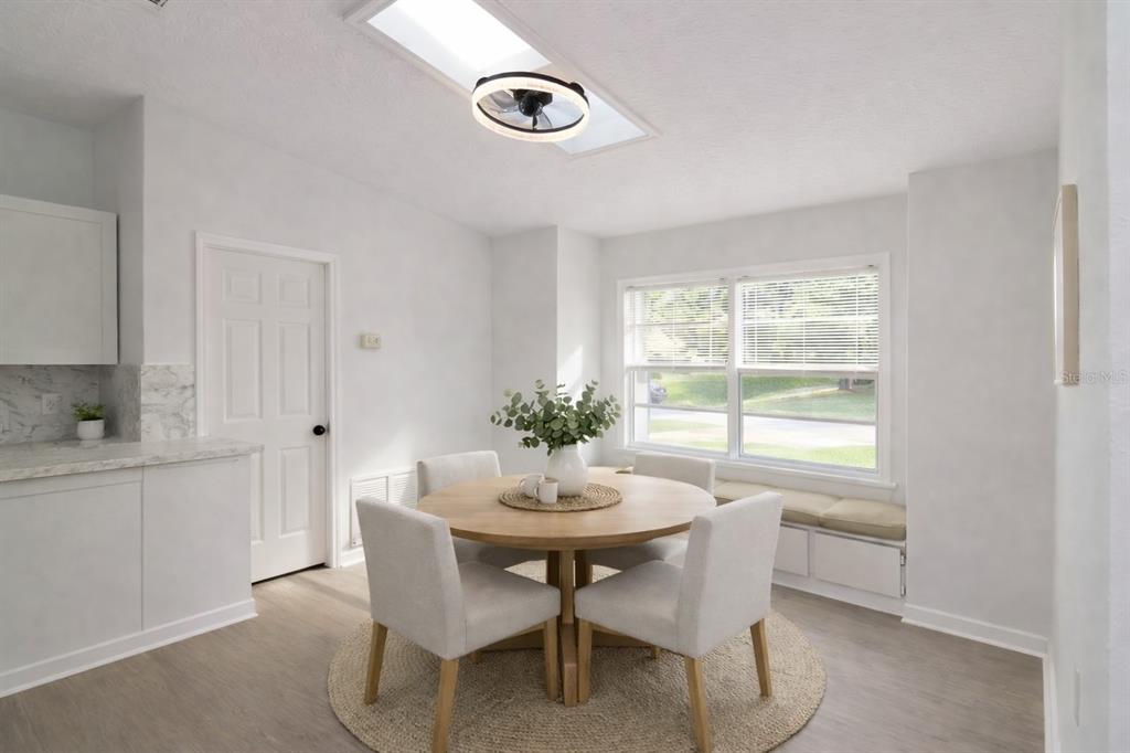 A dining area features a round wooden table, four chairs, a window seat, and a skylight — 711 KEMPTEN STREET NW, PALM BAY, FL