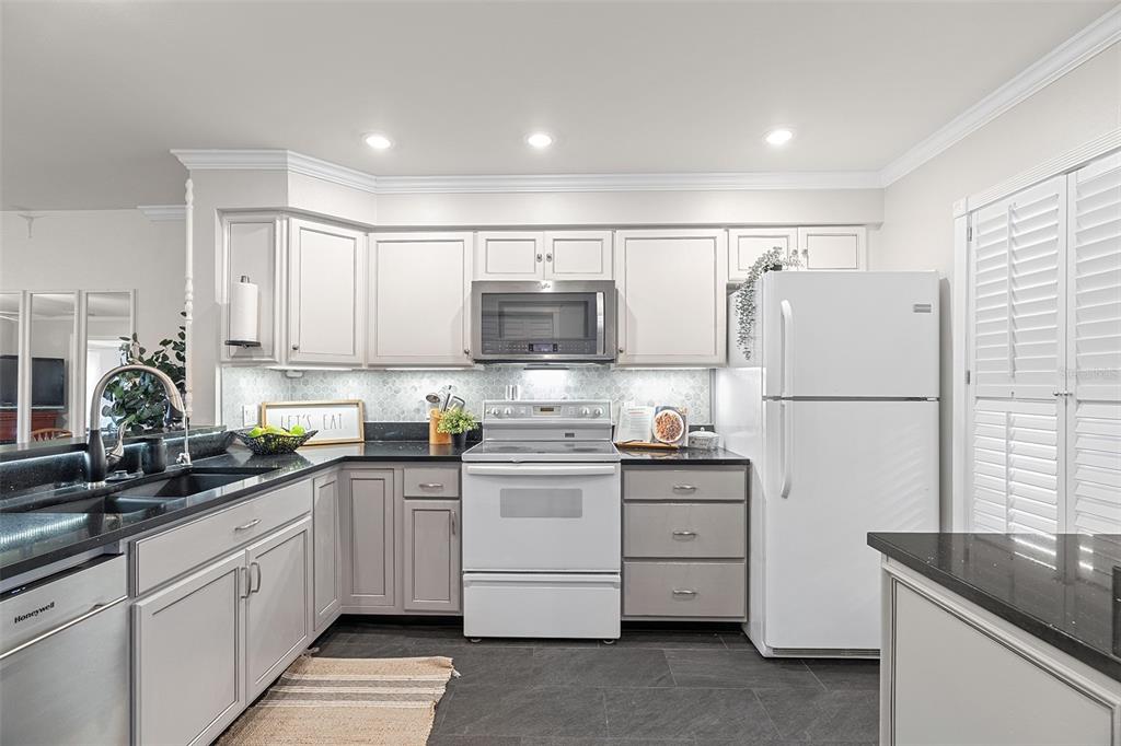 A kitchen features light gray cabinets, black countertops, a white stove, and a white refrigerator — 200 INTERNATIONAL DRIVE UNIT 815, CAPE CANAVERAL, FL