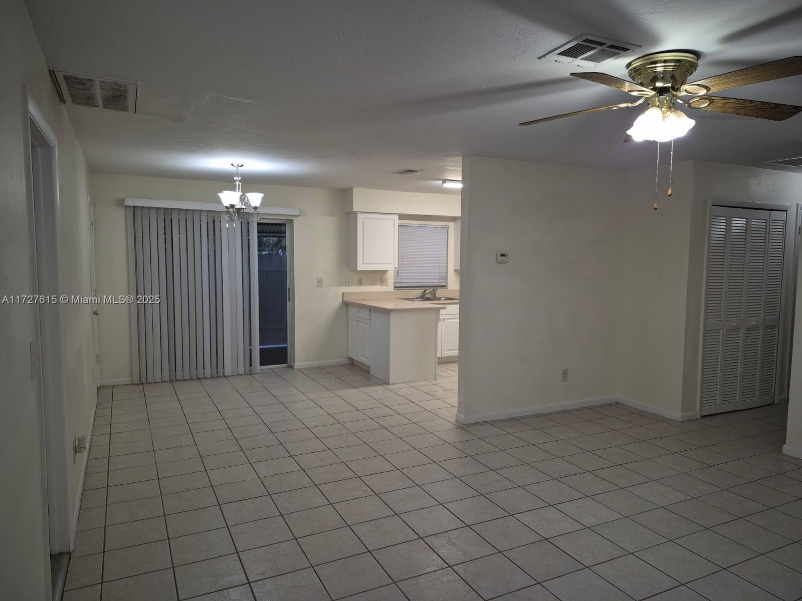 An open-concept living and dining area features white tile flooring, a ceiling fan, and kitchen — 1019 NW 7TH PLACE, Cape Coral FL 33993, CAPE CORAL, FL