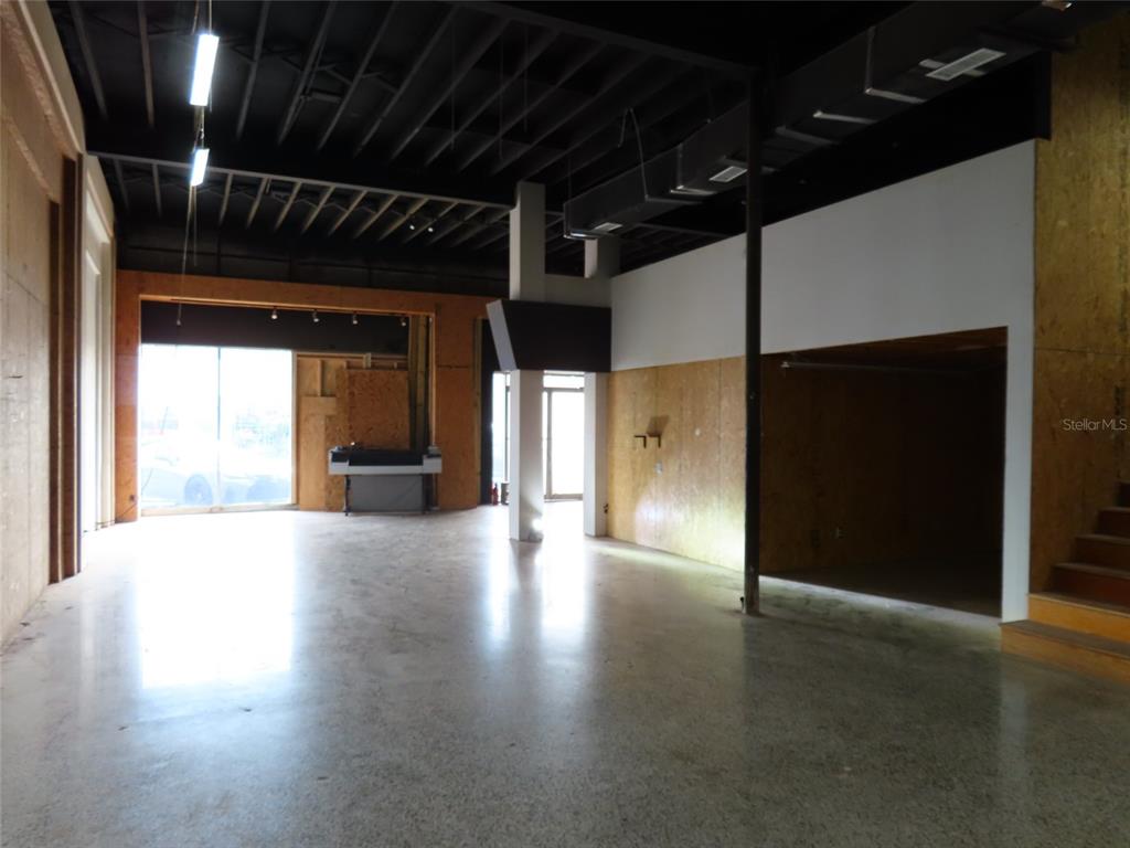 An open commercial space features polished concrete floors, exposed ceiling joists, and plywood wall panels — 4907 N FLORIDA AVENUE, TAMPA, FL