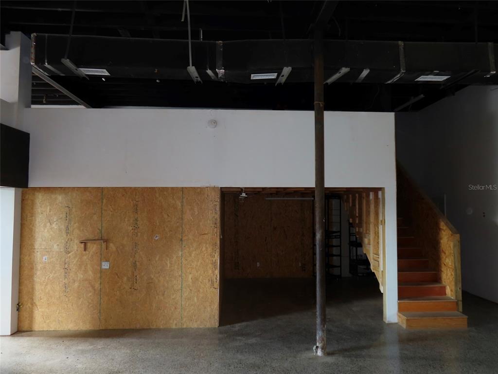 An unfinished commercial space features a wooden partition, a staircase, and exposed ceiling ductwork — 4907 N FLORIDA AVENUE, TAMPA, FL