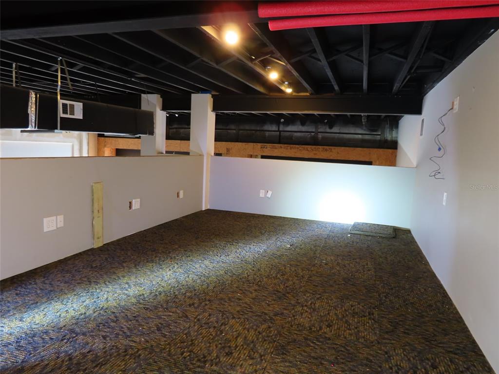 An unfinished room features a dark exposed ceiling, gray walls, and patterned carpet flooring — 4907 N FLORIDA AVENUE, TAMPA, FL
