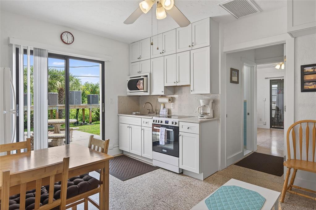 A kitchen with white cabinets, a sliding glass door, and a dining table — 908 VILLAS DRIVE UNIT 14, VENICE, FL