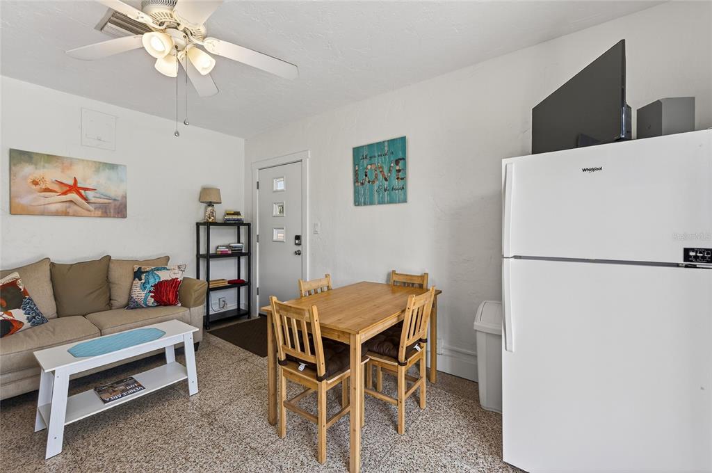 A small living and dining area features a sofa, wooden table, and white refrigerator — 908 VILLAS DRIVE UNIT 14, VENICE, FL