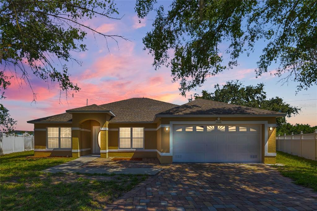 A single-story house with a tan stucco exterior, a two-car garage, and a paved driveway — 2910 LOTUS CT, KISSIMMEE, FL
