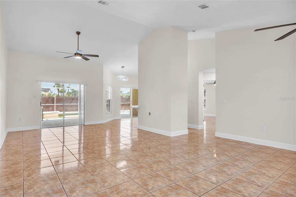 A spacious living area features light-colored walls, tiled floors, a ceiling fan, and sliding doors — 2910 LOTUS CT, KISSIMMEE, FL