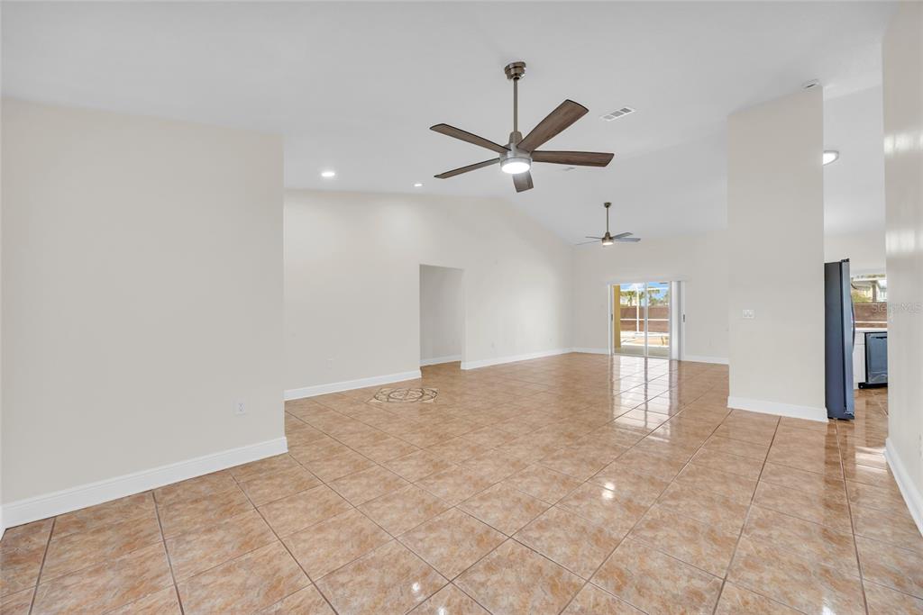 An open-concept living area features light-colored walls, vaulted ceilings with two fans, and tiled flooring — 2910 LOTUS CT, KISSIMMEE, FL