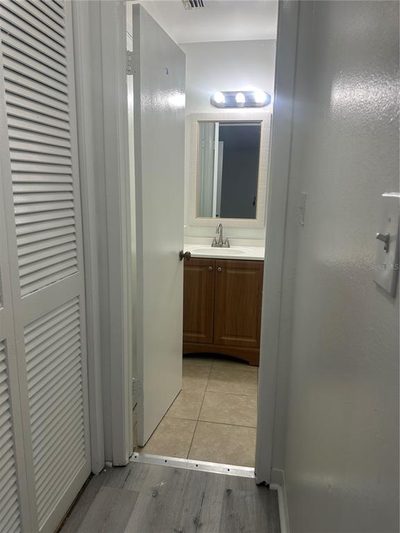 A view through a doorway into a bathroom with a wood vanity and tiled floor — 8426 CAMDEN STREET UNIT D, TAMPA, FL