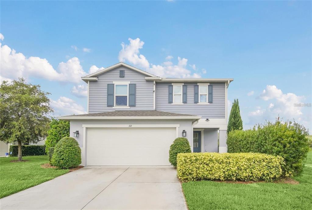 A two-story house with light blue siding, a two-car garage, and a manicured front lawn — 321 PRESERVE POINTE BOULEVARD, DAVENPORT, FL