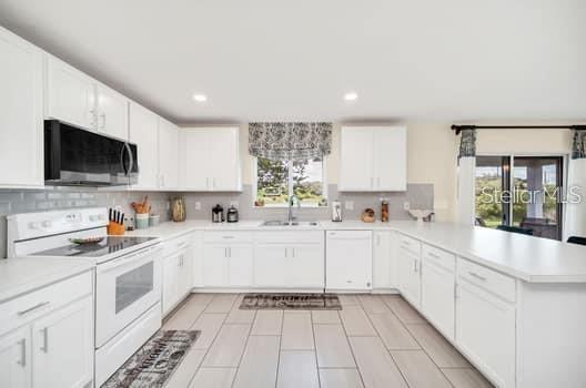 A bright kitchen features white cabinets, stainless steel appliances, and light tile flooring — 321 PRESERVE POINTE BOULEVARD, DAVENPORT, FL