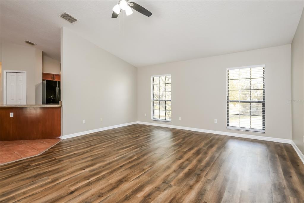 An empty living room features wood-look flooring, light-colored walls, and two windows with blinds — 405 CENTER STREET, ALTAMONTE SPRINGS, FL