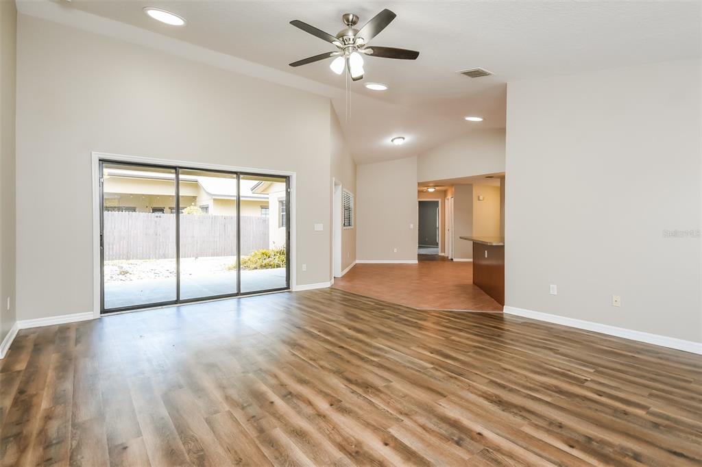 A living room with wood-look flooring, a vaulted ceiling, a ceiling fan, and sliding glass doors — 405 CENTER STREET, ALTAMONTE SPRINGS, FL