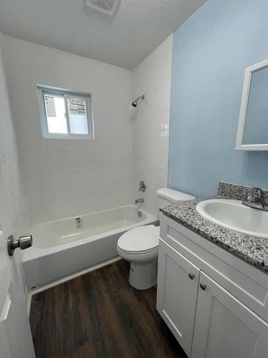 A small bathroom features a white tub, a toilet, and a vanity with granite countertops — 1109 NW 6th Avenue Apt 1, Pompano Beach FL 33060, POMPANO BEACH, FL