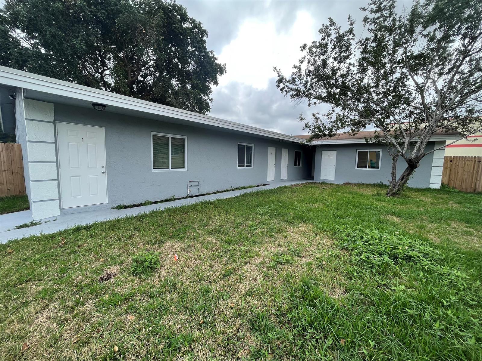 A gray, single-story apartment building with multiple white doors and a grassy yard — 1109 NW 6th Avenue Apt 1, Pompano Beach FL 33060, POMPANO BEACH, FL
