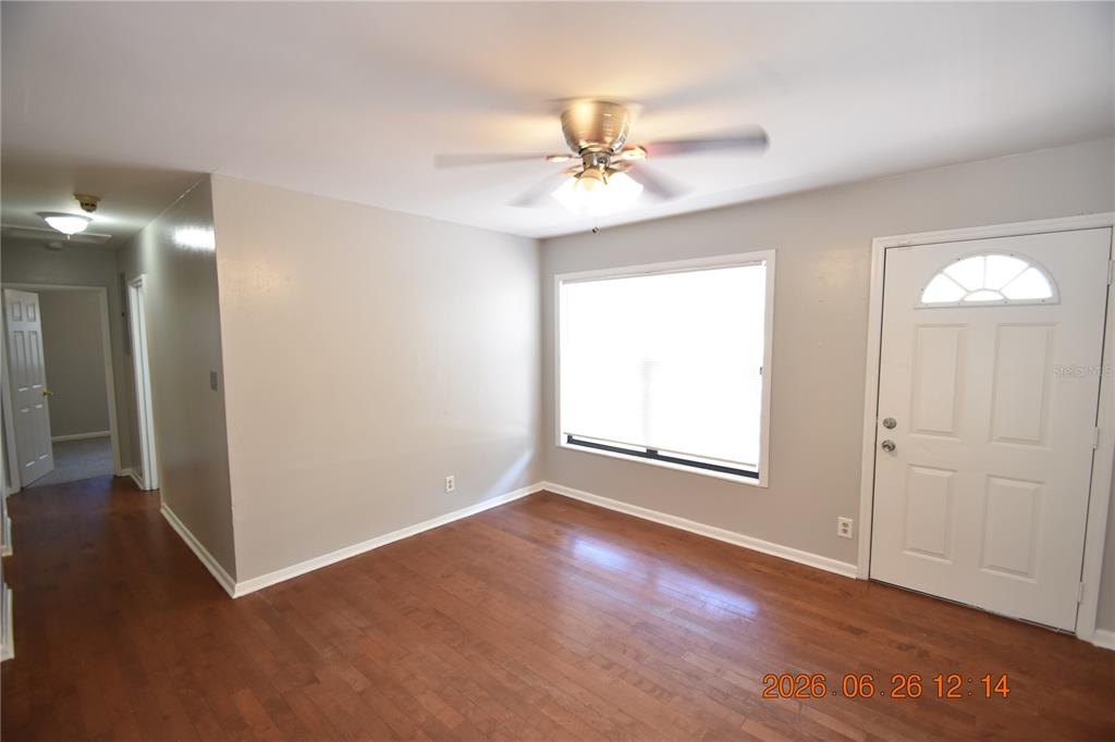 An empty room features hardwood floors, a ceiling fan, a window, and a white door — 4414 W WYOMING AVENUE, TAMPA, FL