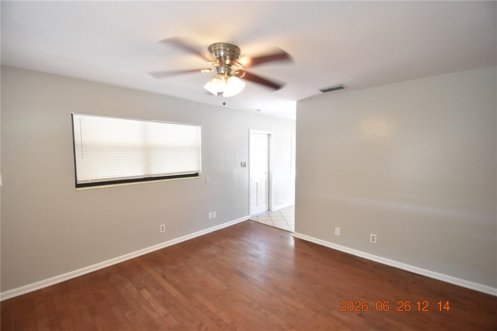An empty room features light gray walls, hardwood flooring, a ceiling fan, and a window — 4414 W WYOMING AVENUE, TAMPA, FL