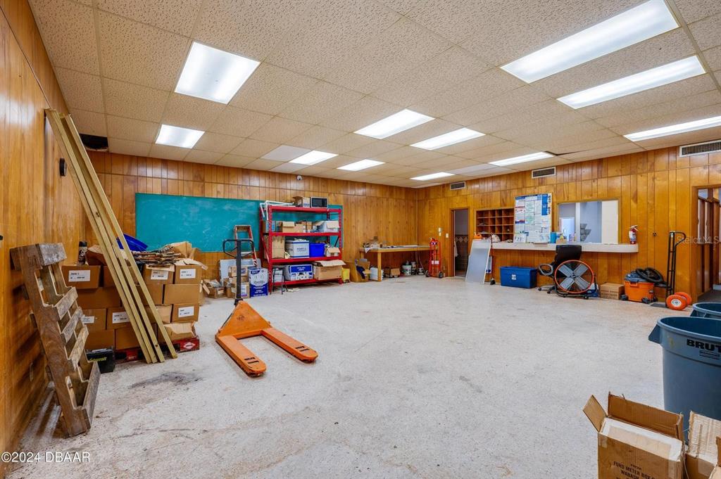 A large, empty storage or workshop room with wood-paneled walls and a drop ceiling — 116 CENTER STREET, DAYTONA BEACH, FL