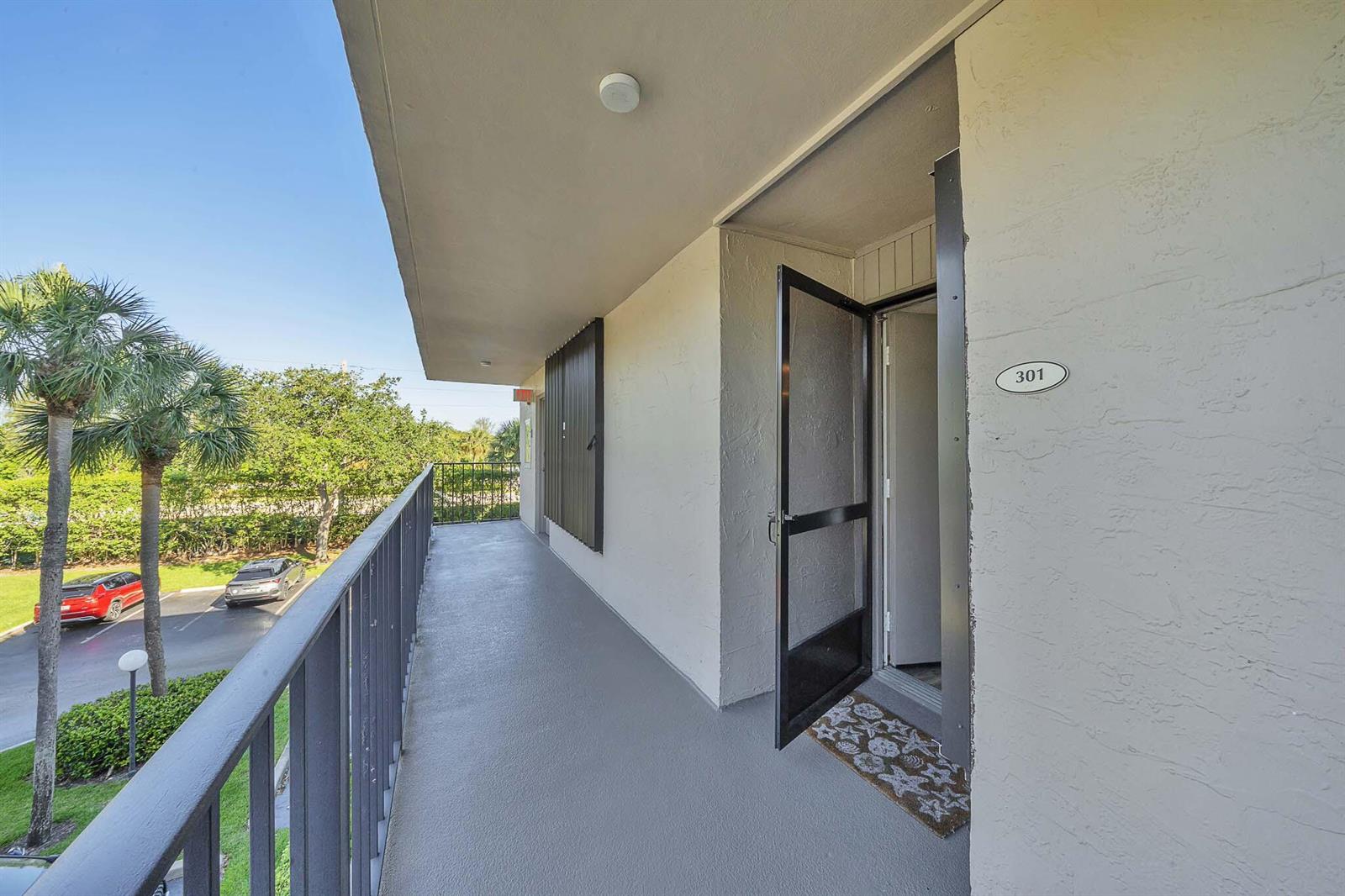 An exterior walkway leads to the entrance of unit 301, featuring a metal railing — 17 Royal Palm Way # 3010, Boca Raton FL 33432, BOCA RATON, FL