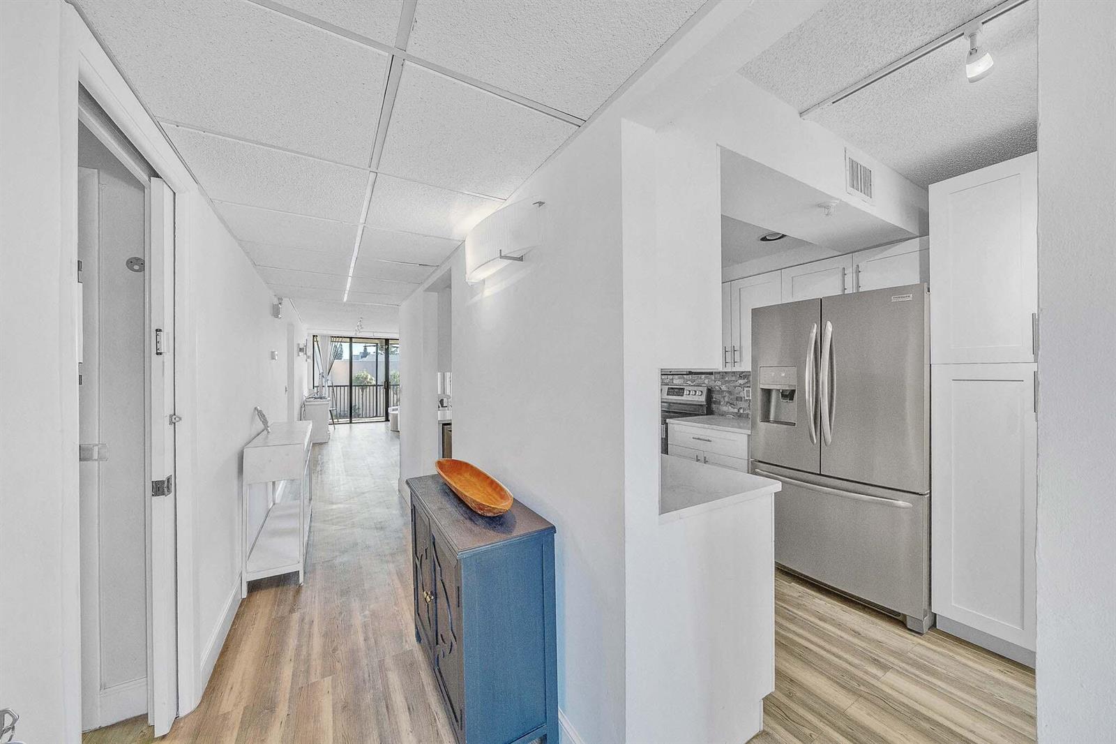 A hallway leads to a balcony, with a kitchen featuring stainless steel appliances on the right — 17 Royal Palm Way # 3010, Boca Raton FL 33432, BOCA RATON, FL