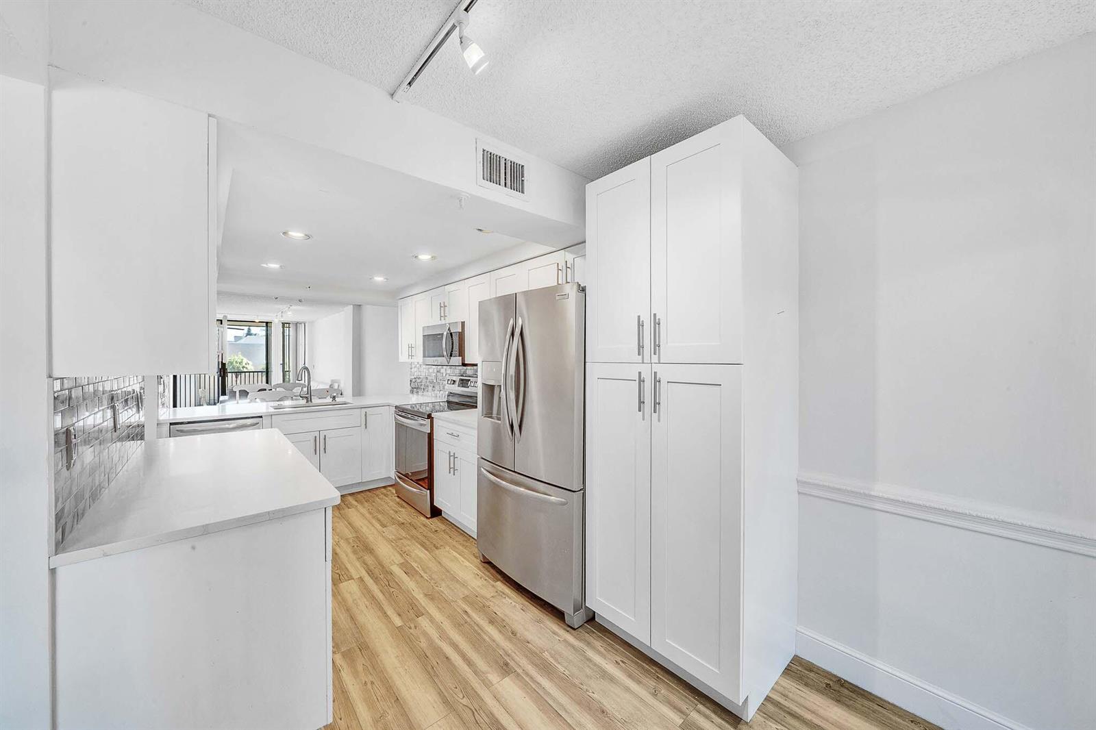 A kitchen with white cabinets, stainless steel appliances, and light wood-look flooring — 17 Royal Palm Way # 3010, Boca Raton FL 33432, BOCA RATON, FL