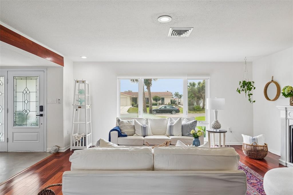 A living room features white sofas, dark hardwood floors, and a large window overlooking a street — 4379 44TH STREET S, ST PETERSBURG, FL