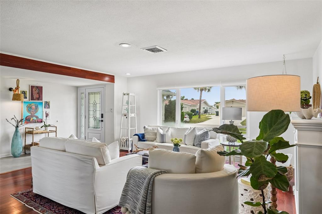 A bright living room features white sofas, hardwood floors, and a view of a neighborhood street — 4379 44TH STREET S, ST PETERSBURG, FL