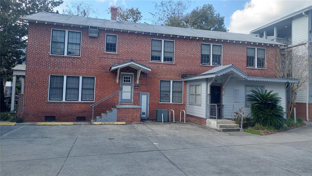 A two-story red brick building features a concrete parking lot and two covered entryways — 1615 NW 3RD AVENUE, GAINESVILLE, FL