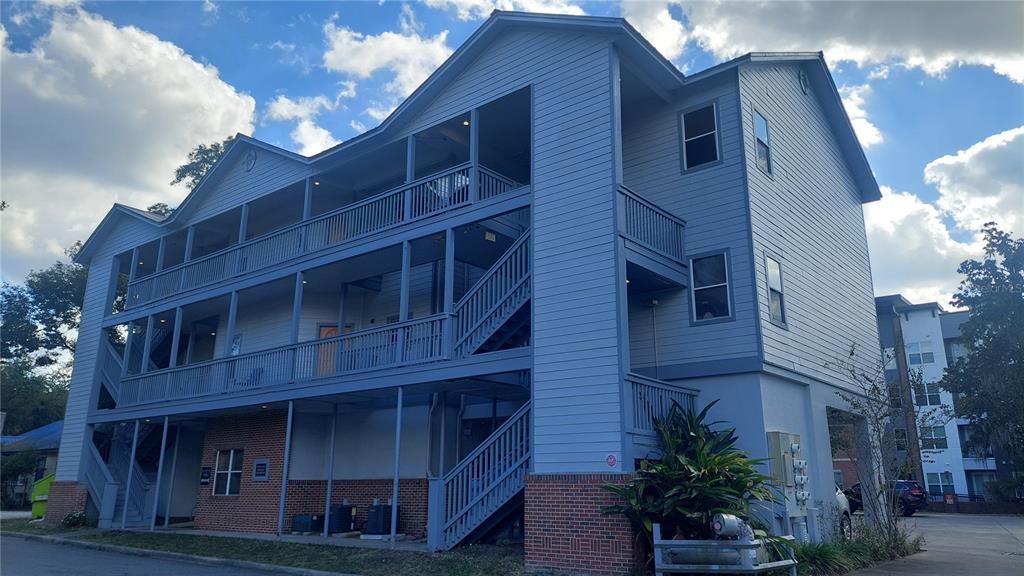 A three-story apartment building with blue siding, exterior staircases, and a brick-accented ground level — 1615 NW 3RD AVENUE, GAINESVILLE, FL