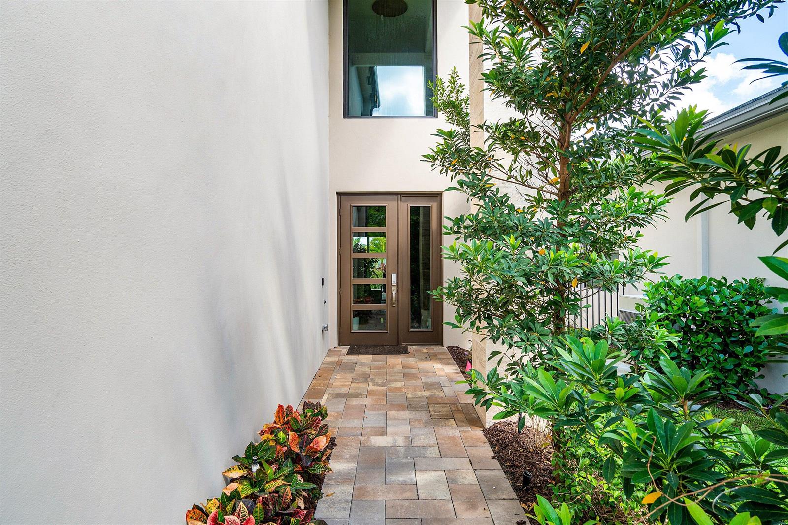 A paved walkway leads to a modern front door with a tall window above it — 8233 Crystal Downs Avenue, Boca Raton FL 33434, BOCA RATON, FL