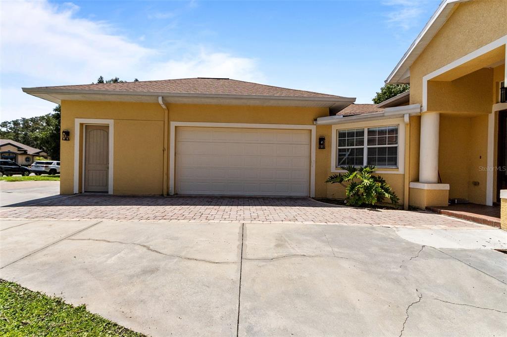 A yellow house exterior features a two-car garage, a side door, and a paved driveway — 4116 WOODACRE LANE, TAMPA, FL