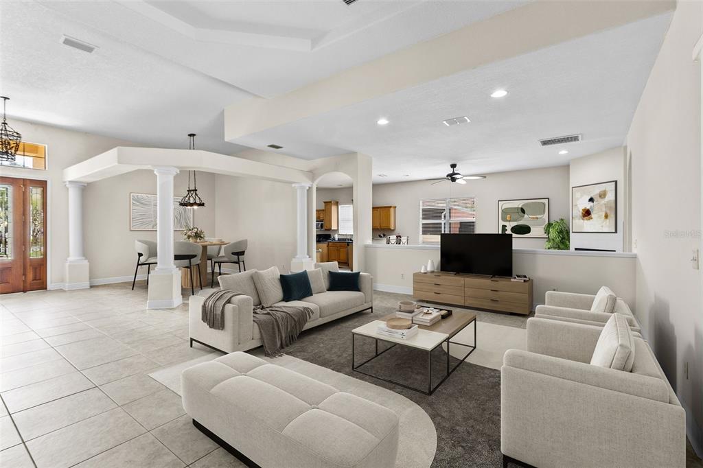 An open-concept living room features tile flooring, a dining area with columns, and neutral furniture — 4116 WOODACRE LANE, TAMPA, FL