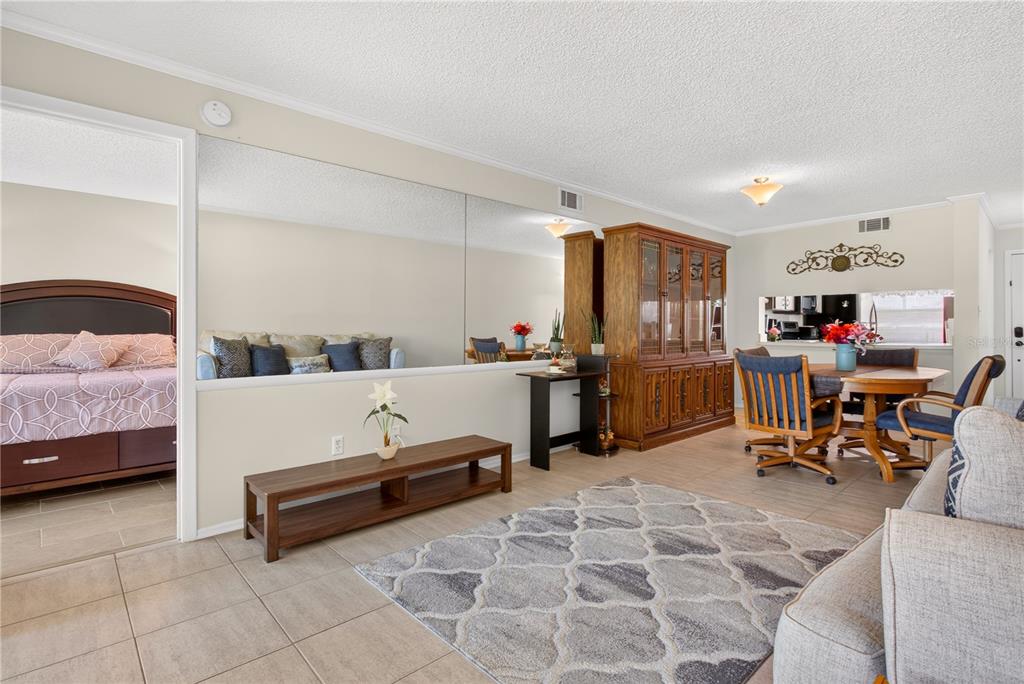A living room with tile floors, a large mirror, a wooden hutch, and dining area — 3276 CANDLE RIDGE COURT UNIT 202, ORLANDO, FL