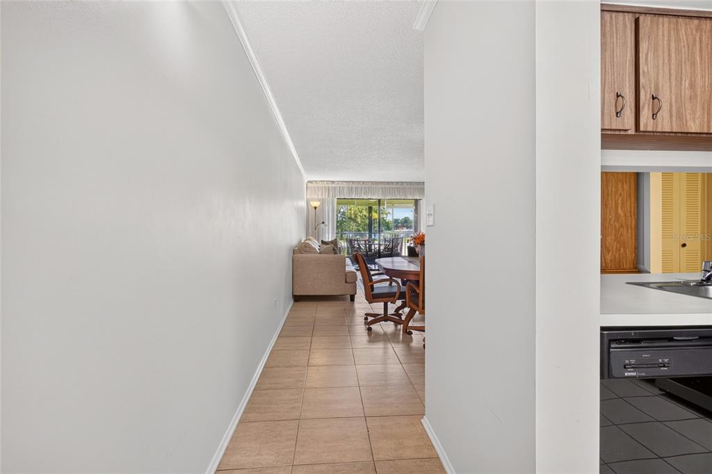 A tiled hallway leads from a kitchen area toward a living room with sliding doors — 3276 CANDLE RIDGE COURT UNIT 202, ORLANDO, FL