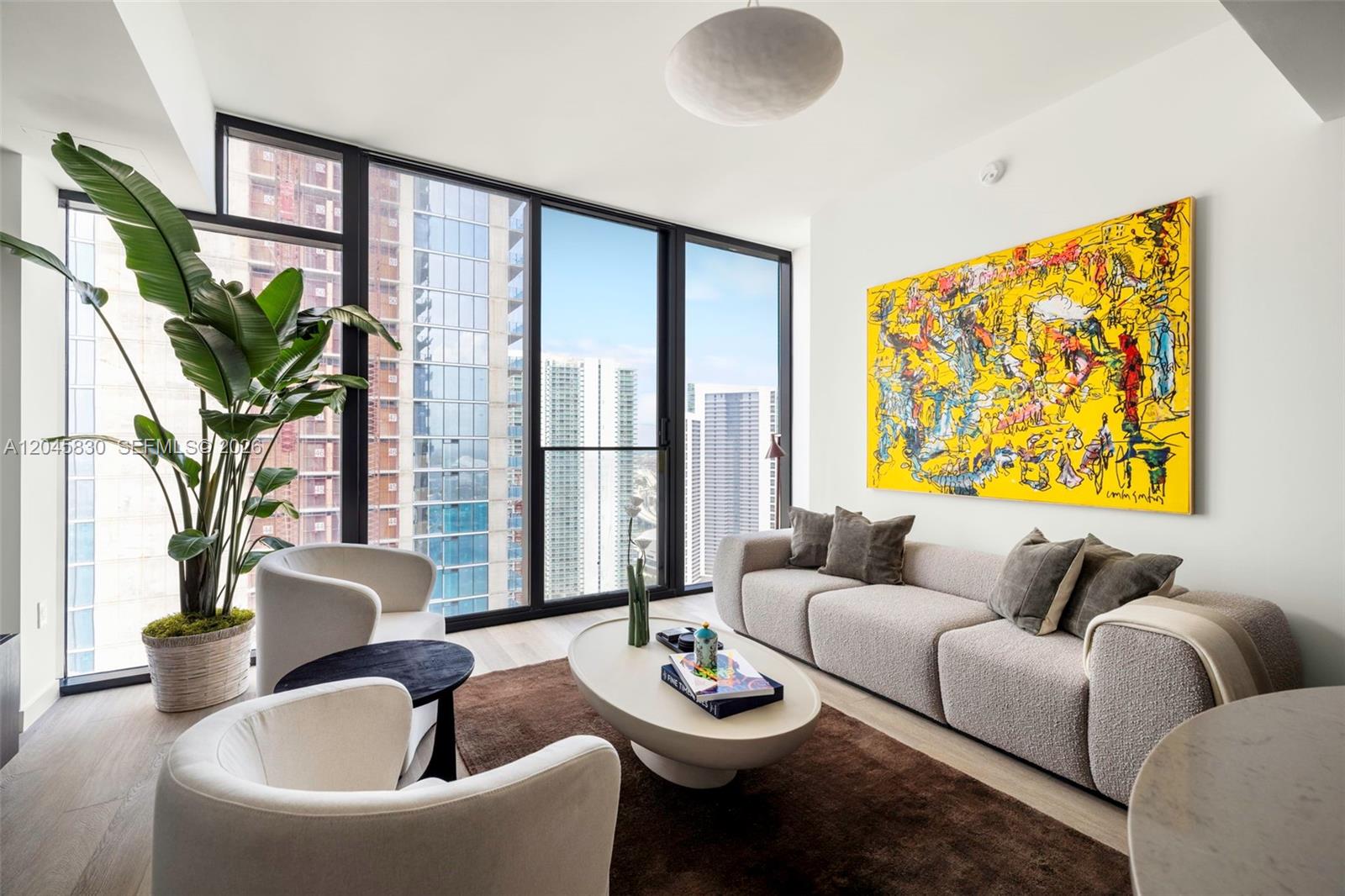 A modern living room features a textured sofa, two white armchairs, and a large yellow painting — 20 NE 11th St # 4503, Miami FL 33132, MIAMI, FL