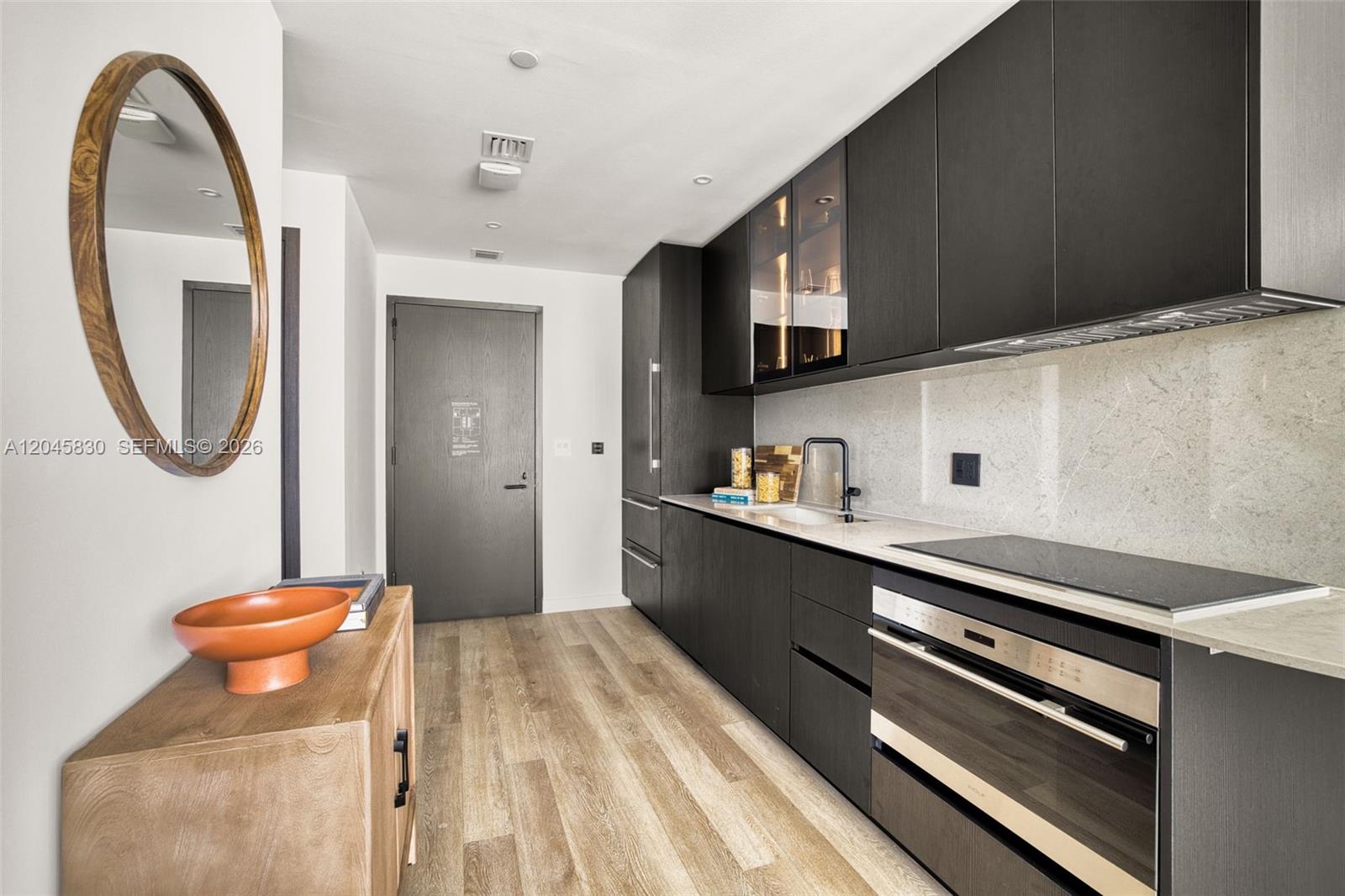 A modern kitchen features dark cabinetry, light countertops, and wood-look flooring — 20 NE 11th St # 4503, Miami FL 33132, MIAMI, FL