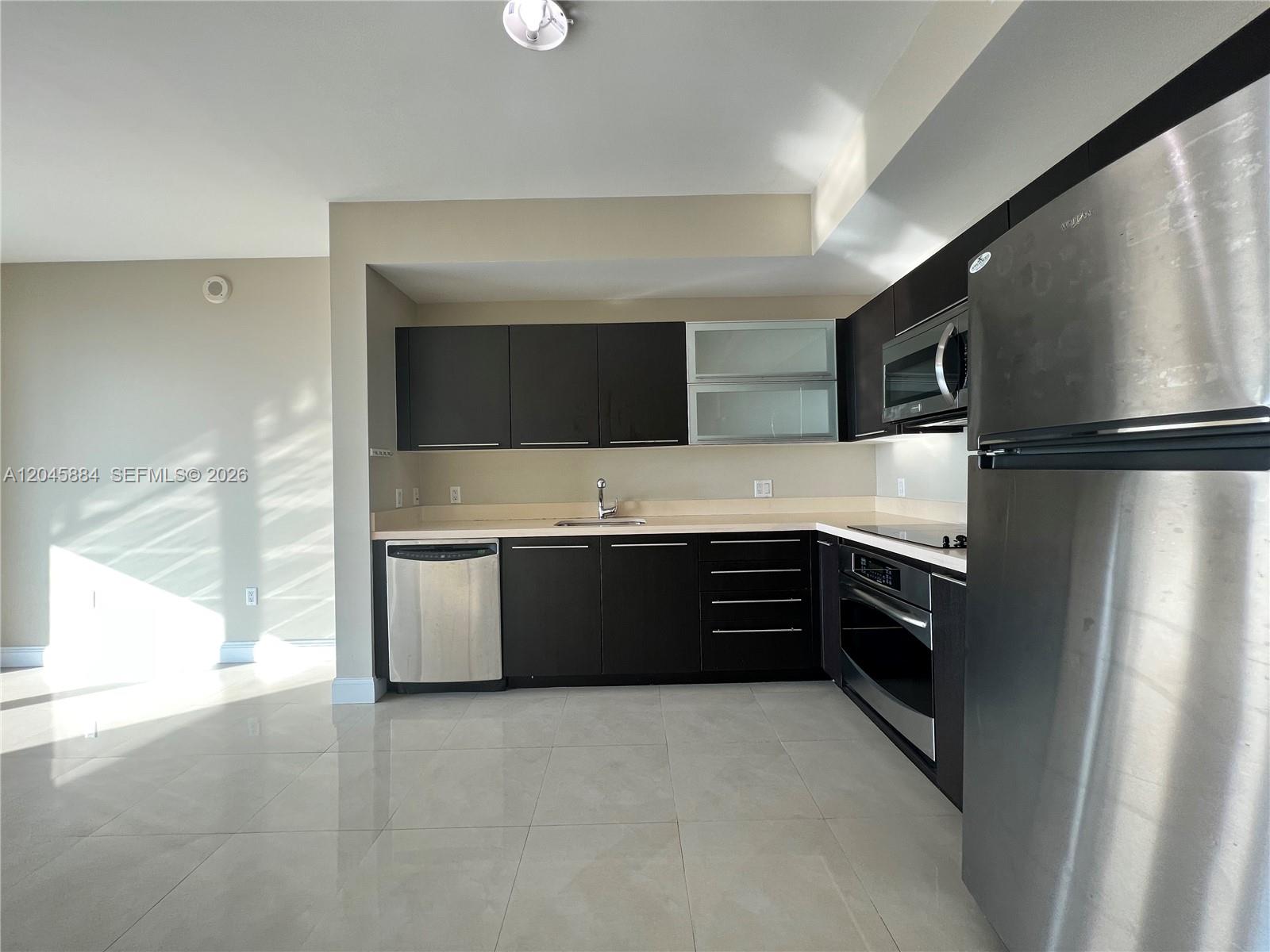 A modern kitchen features dark wood cabinets, stainless steel appliances, and light-colored tile flooring — 90 SW 3rd St # 1710, Miami FL 33130, MIAMI, FL