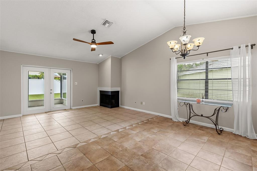 A living room with tile flooring, a corner fireplace, a ceiling fan, and a chandelier — 1275 BRIDLEBROOK DRIVE, CASSELBERRY, FL