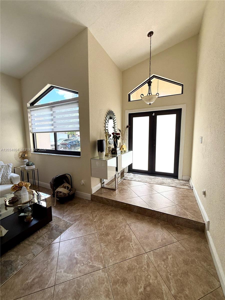 An entryway with a vaulted ceiling, tiled floor, and double glass doors — 8731 NW 153rd Ter, Miami Lakes FL 33018, MIAMI LAKES, FL