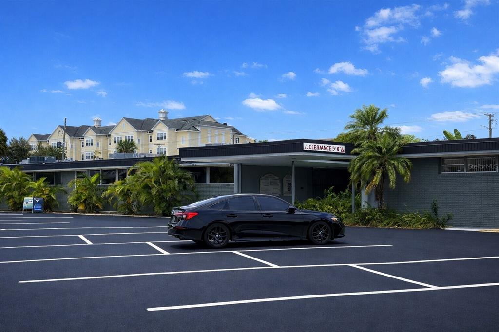A black sedan is parked in front of a low-rise building with a clearance sign — 1201 S HIGHLAND AVENUE UNIT 7, CLEARWATER, FL