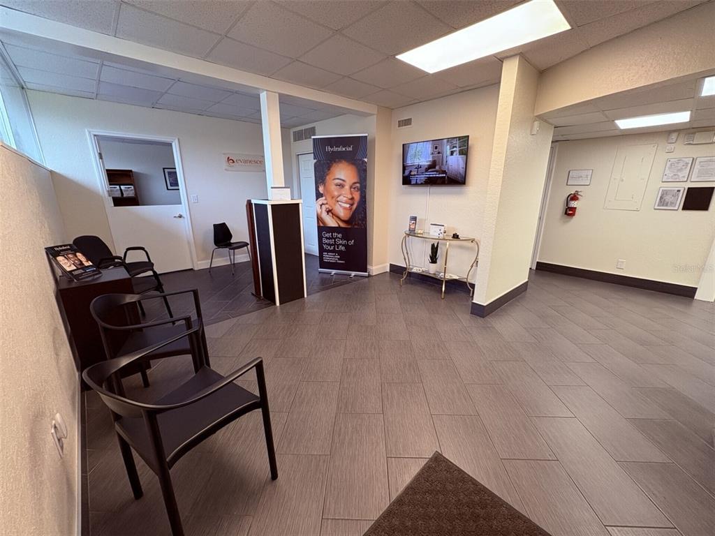 A waiting room features gray tile flooring, black chairs, a reception desk, and wall-mounted signage — 1201 S HIGHLAND AVENUE UNIT 7, CLEARWATER, FL