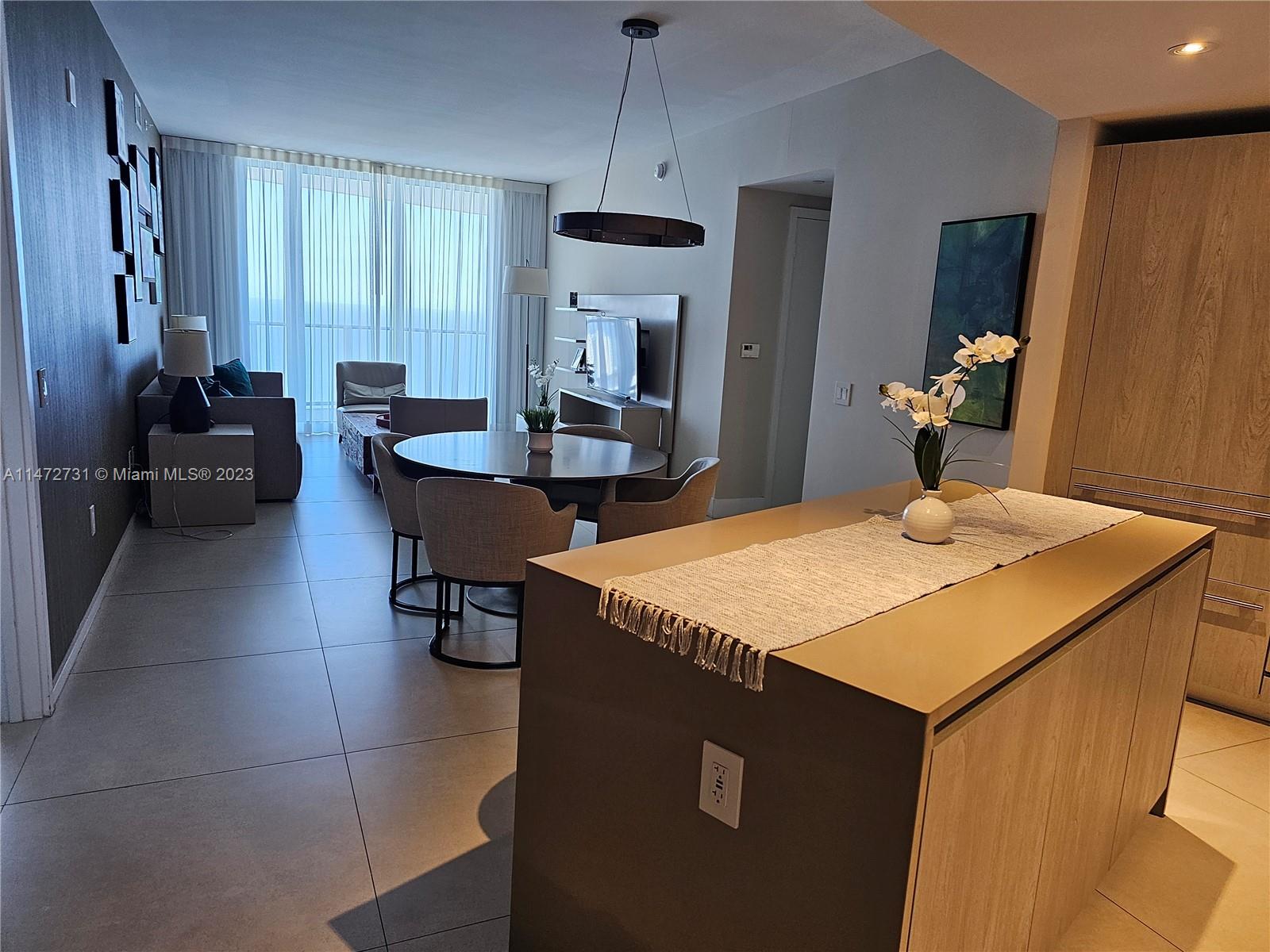 A modern open-concept living and dining area features tile floors, a kitchen island, and floor-to-ceiling windows — 4111 S Ocean Dr # 3608, Hollywood FL 33019, HOLLYWOOD, FL