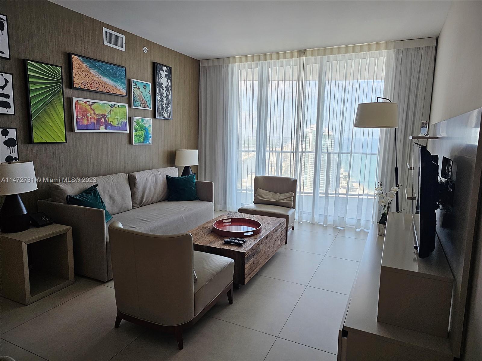 A living room features a beige sofa, a wooden coffee table, and floor-to-ceiling windows — 4111 S Ocean Dr # 3608, Hollywood FL 33019, HOLLYWOOD, FL