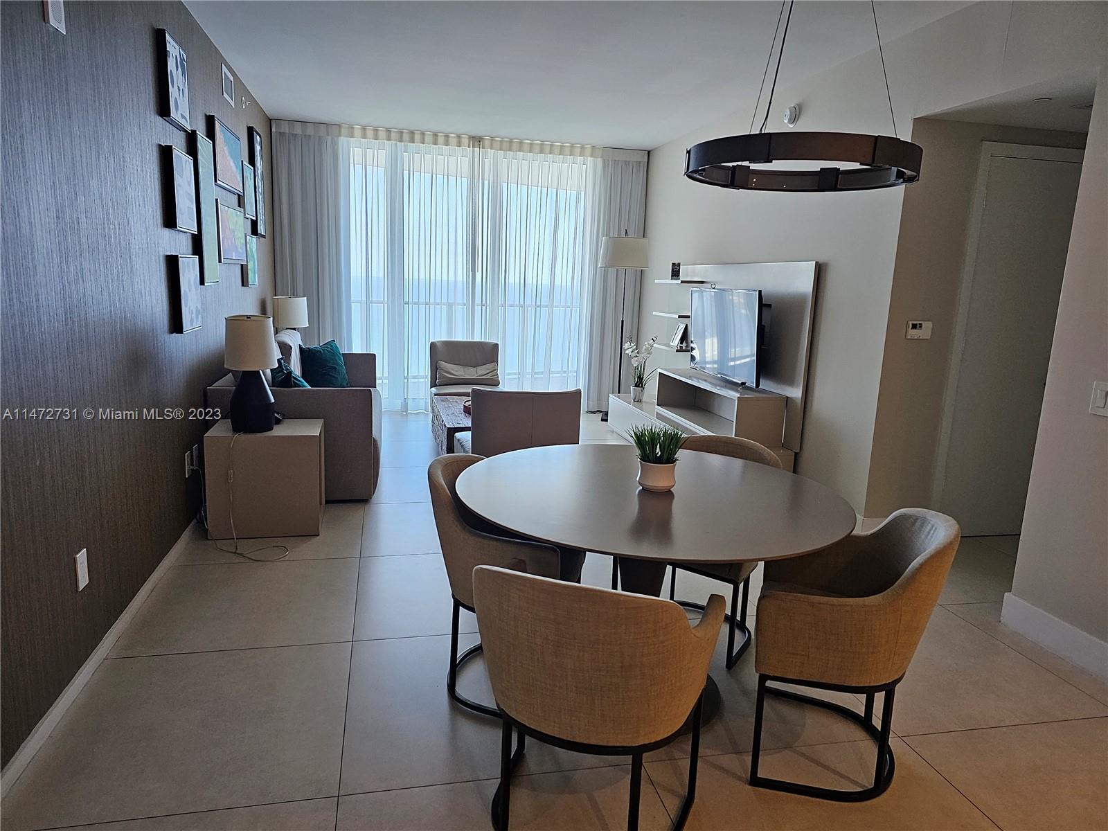 A modern living and dining area features a round table, neutral furniture, and floor-to-ceiling windows — 4111 S Ocean Dr # 3608, Hollywood FL 33019, HOLLYWOOD, FL
