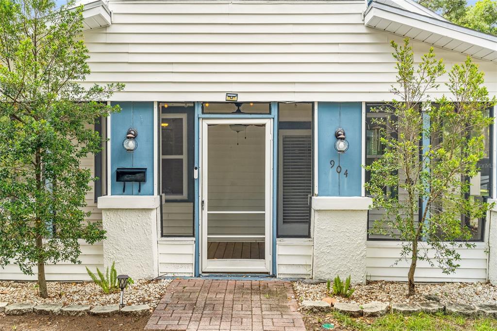 A white house exterior features a blue-accented screened front porch and a brick walkway — 904 W HENRY AVENUE, TAMPA, FL