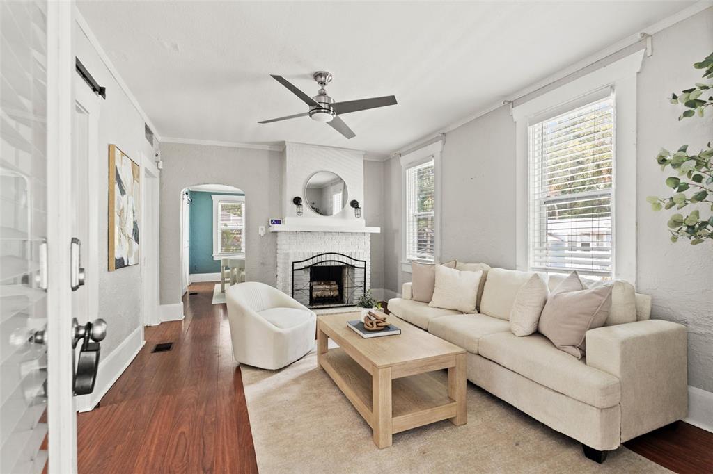 A living room features a white brick fireplace, a beige sofa, and hardwood floors — 904 W HENRY AVENUE, TAMPA, FL