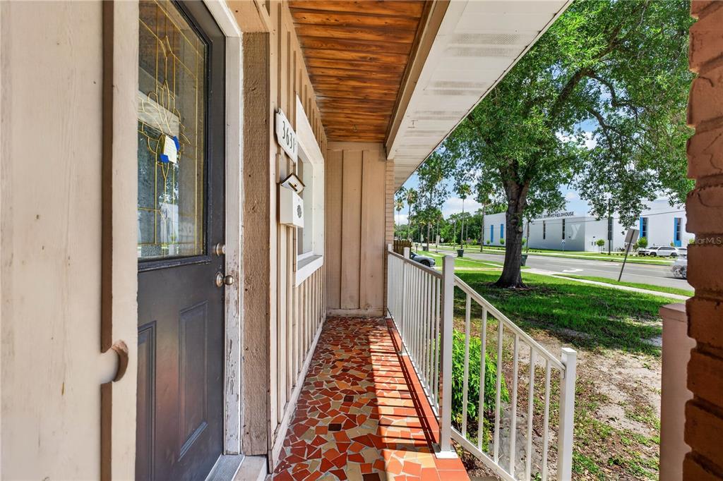 A covered front porch features a mosaic tile floor, a dark door, and white railings — 3631 CLEVELAND HEIGHTS BOULEVARD, LAKELAND, FL