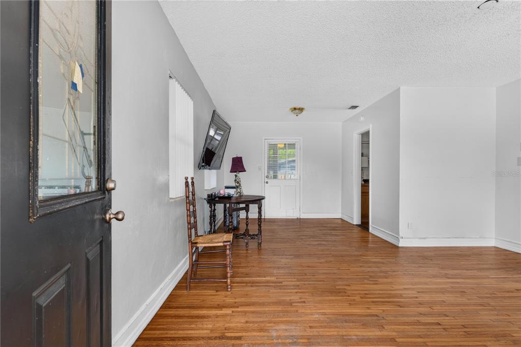 An interior view of a room with hardwood floors, white walls, and a wooden chair — 3631 CLEVELAND HEIGHTS BOULEVARD, LAKELAND, FL
