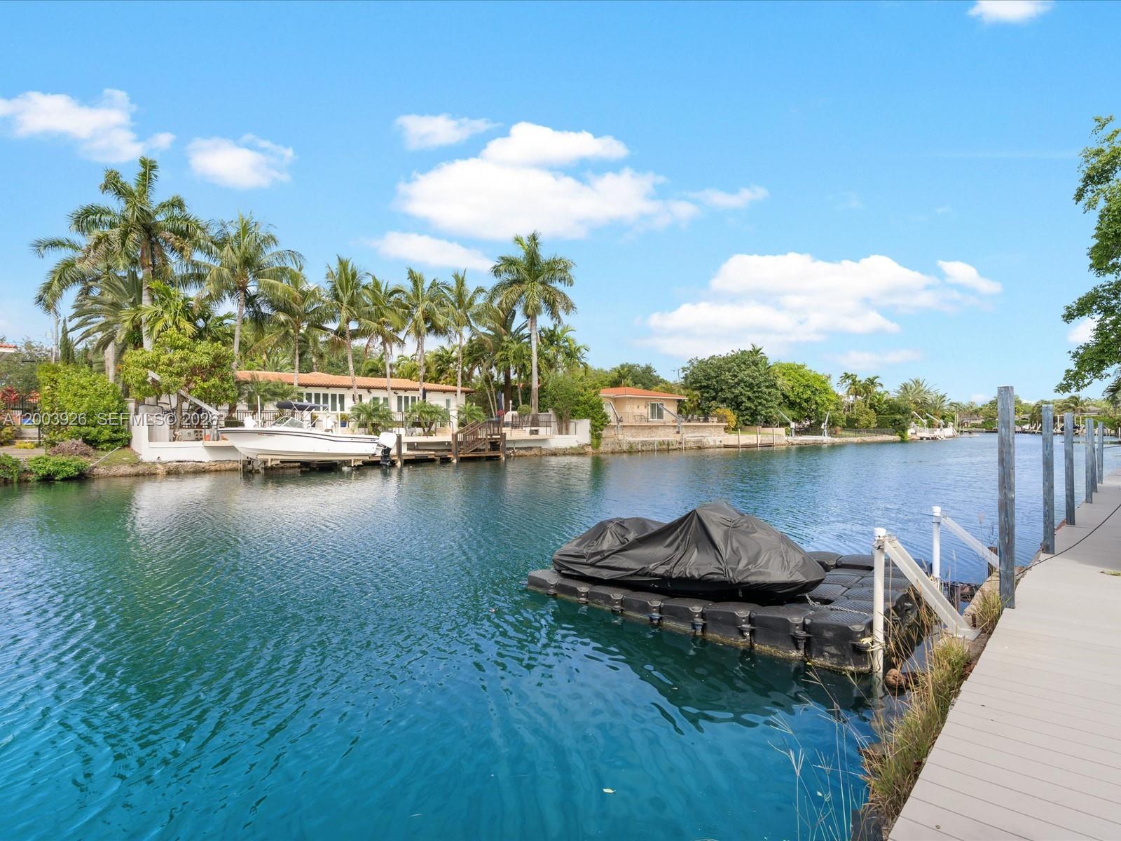 A jet ski sits on a floating dock in a canal beside a residential property — 5000 Riviera Dr, Coral Gables FL 33146, CORAL GABLES, FL