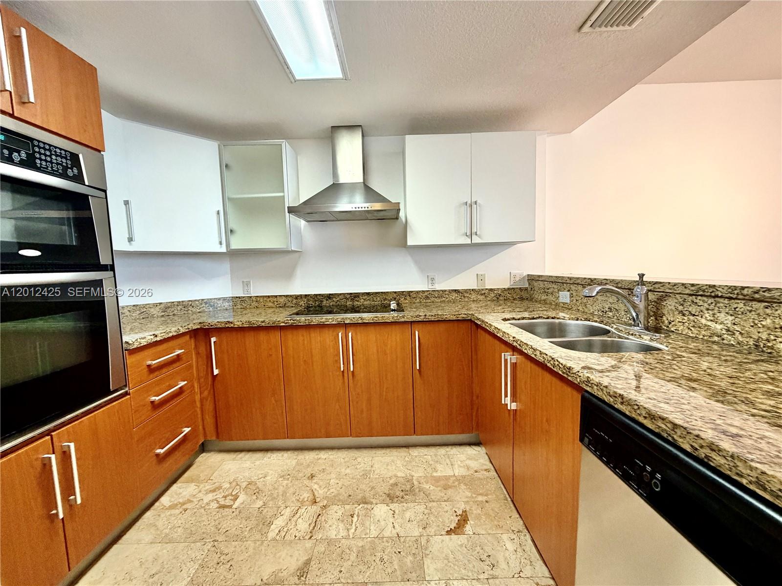A kitchen features wood cabinets, white upper cabinets, granite countertops, and stainless steel appliances — 170 SE 14th St # 2906, Miami FL 33131, MIAMI, FL